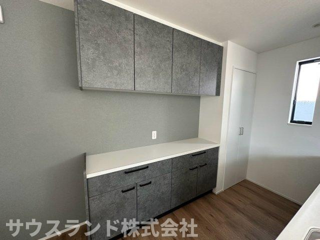 八王子市元本郷町22期のキッチン|シックなグレーの壁面に馴染む、大容量のカップボードが備え付けられています！食器や調理家電などをたっぷりと収納でき、作業スペースも確保されています。いつでもすっきりと片付いた美しいキッチンを保てます。