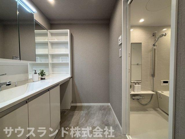 マクシスタワーズアーバンデュオの脱衣所|洗面用品を美しく整えられる豊富な収納と、横幅のある洗面カウンターが魅力。身支度をゆったり行える広さに加え、浴室が隣接した使いやすい動線で、毎日の家事や入浴準備も心地よく進められます。