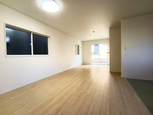 クレイドルガーデン下松市桜町 第1の居間・リビング|大きな窓から明るい自然光が差し込む伸びやかなLDK。白を基調とした壁と温かみのあるフローリングが清潔感あふれる空間を演出します。右手にはリビングと繋がる和室コーナーがあり、開放感があります。