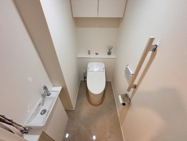 快適な温水洗浄便座付きのトイレです。手洗いカウンターを完備し、上部には便利な吊戸棚を備えた機能的な設計。清潔感のある落ち着いた空間、手すりも設置されており、どなた様にも使いやすい配慮がなされています。