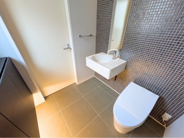 白水台6丁目戸建のトイレ|落ち着いた色調のタイル壁がおしゃれなトイレ空間です。独立した手洗い器付きで衛生的に使用できます。