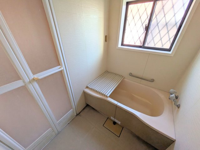 水泥町戸建の浴室|小窓から自然光が入る浴室には手すりが設置されており、立ち座りを優しくサポートします。