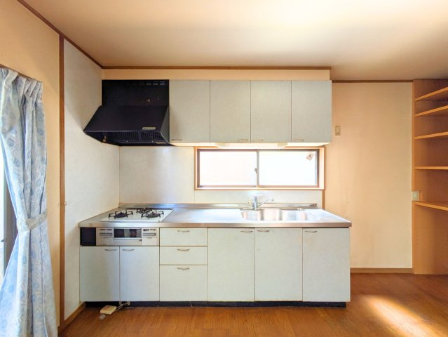 水泥町戸建のキッチン|上部に棚を備えた壁付けキッチンは、作業スペースが広くお料理がはかどる快適な空間です。