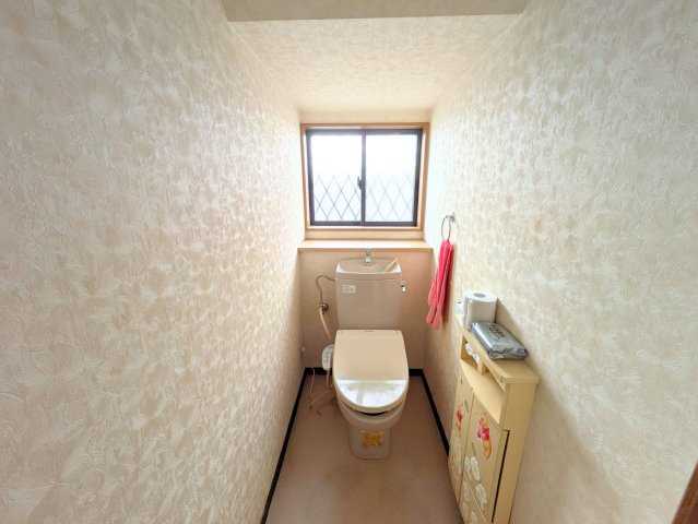 水泥町戸建のトイレ|自然光が入る明るいトイレは、ペーパーや清掃用品をすっきり仕舞える棚を備えております。