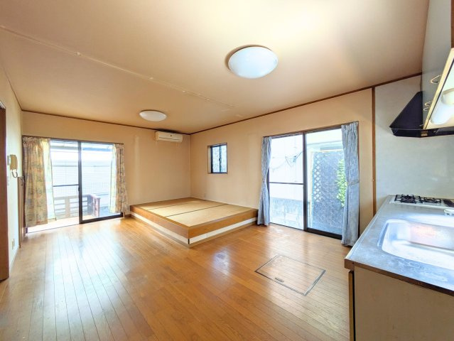 水泥町戸建の居間・リビング|大きな窓から明るい陽光が差し込むリビングは、小上がりの畳コーナーでゆったり寛げる空間です。