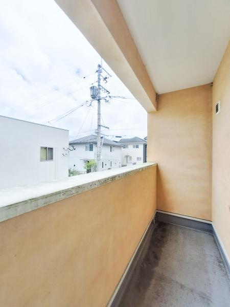 京が丘南3丁目　中古のバルコニー|明るい色合いの壁で開放感のあるバルコニーです。周囲の住宅街を見渡せる位置にあり屋根付きで天候の影響も受けにくい仕様です。シンプルな設計が空間の使いやすさを感じさせます。手すりが高めで安心感もあります。