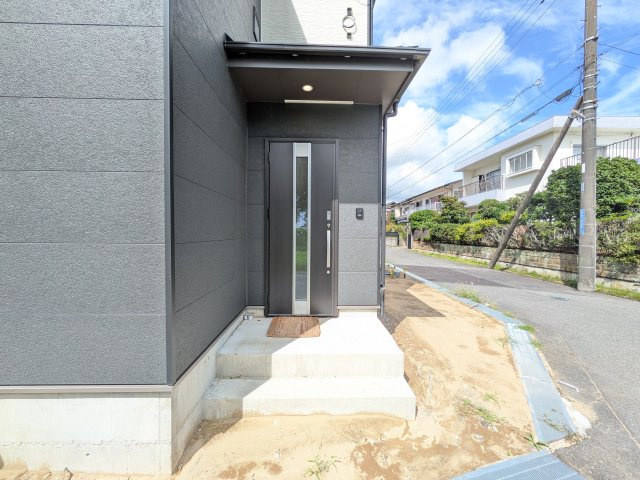 我孫子市青山台Ⅱ　新築戸建て　Ｂ号棟の玄関|お洒落な玄関ドアと洗練された外壁デザイン。家の顔にふさわしい上質な佇まいで、ご家族やお客様を迎えます。