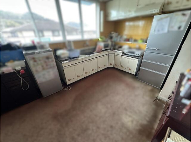 「店舗付き住宅」香南市野市町　中古一戸建てのキッチン|シンクとコンロの作業スペースが広いL字型キッチンは窓付きで手元が明るく換気もしやすい構造、日々の調理や片付けがスムーズに行えます