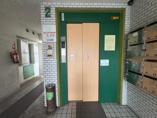 つかさアーバングリーン岩田のエントランス|エントランスには明るい色合いのエレベーターが設置されています。郵便ポストが並んでおり整理された空間です。エレベーター横には掲示板や消火器もあり共用部の機能性が感じられます。