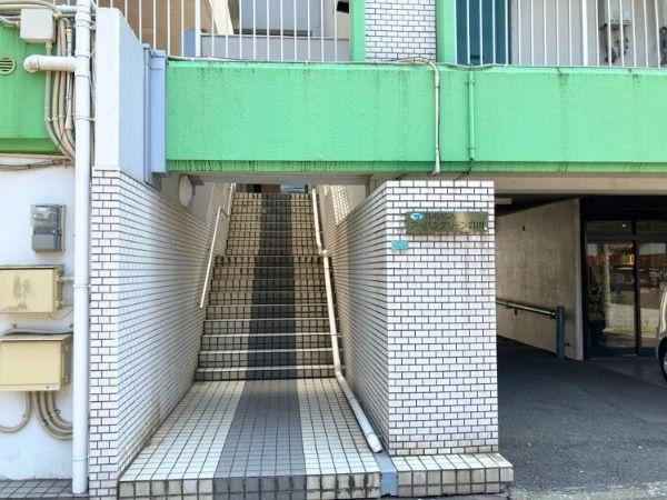 つかさアーバングリーン岩田のエントランス|エントランスにはタイル張りの階段があり手すりも設置されています。明るいグリーンのアクセントが印象的です。建物の入り口が屋根付きで雨の日にも便利です。エントランス周辺は整然とした印象です。