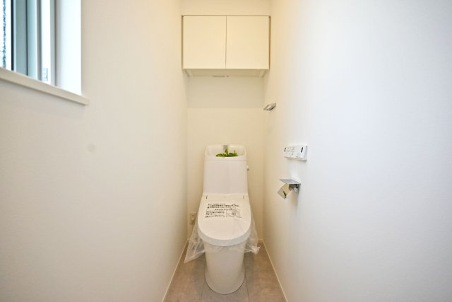 尼崎市南武庫之荘4丁目新築一戸建て│1LDK+2S+並列駐車2台可のトイレ|トイレには換気扇と小窓が配置されています。温感便座や温水洗浄、水栓一体などの機能が装備されたウォッシュレットトイレを1階と2階に1か所ずつ配置しています。