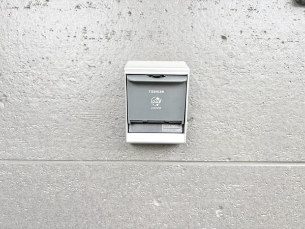藤沢市城南２丁目の新築一戸建のその他|TOSHIBA製のEV充電用コンセントが設置されています。安心して充電ができる設備環境です。壁面にしっかりと取り付けられており使いやすさにも配慮されています。外観もシンプルで建物に調和しています。