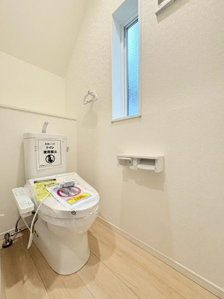 藤沢市城南２丁目の新築一戸建のトイレ|清潔感のあるトイレです。窓付きで明るい空間が広がります。壁面の小物置きやペーパーホルダーも整っています。床は明るい色合いで圧迫感を感じにくい印象です。