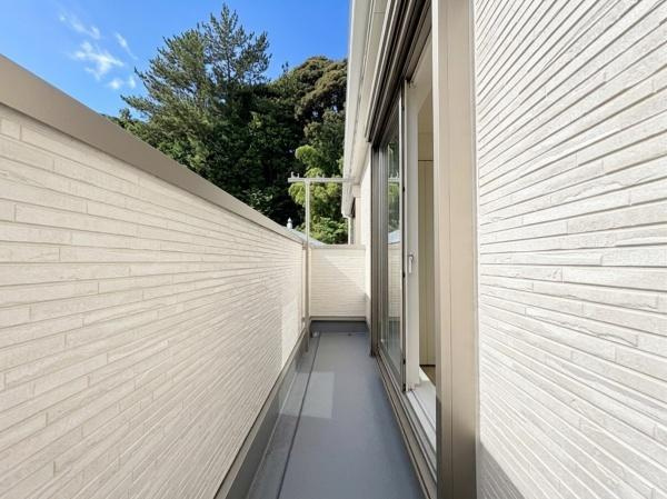 藤沢市城南２丁目の新築一戸建のバルコニー|明るい日差しが差し込むバルコニーです。壁の高さがしっかりとあり外からの視線が気になりにくい設計です。隣接する窓から室内へのアクセスも便利です。バルコニーからは緑が見え自然を感じられる空間です。