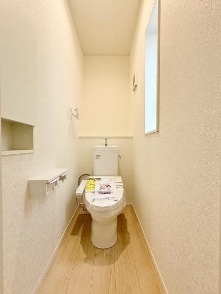 藤沢市城南２丁目の新築一戸建のトイレ|明るい雰囲気のあるトイレです。壁紙や床材はシンプルで清潔感があります。窓から自然光が入り空間が広く感じられます。必要な収納やペーパーホルダーも備わっています。