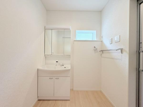 藤沢市城南２丁目の新築一戸建の独立洗面台|明るく清潔感のある洗面台は収納スペースも確保されており機能的です。窓からの自然光が入りやすい設計が特徴的です。すっきりとした内装で手入れもしやすいです。リネンタオルバーも設置され実用性が高い空間です。