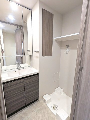 CREATIF秋葉原の洗面所|トイレと独立した洗面室、2面鏡付・ハンドシャワー付の洗面台、室内洗濯機置場は排水溝のお手入れがし易く手前中央に配置し、足高の防水パン、向かって左に収納付です