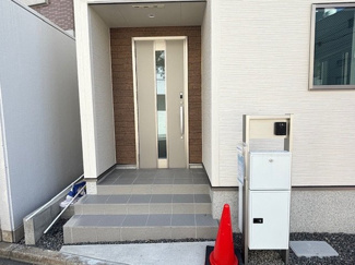 【玄関】 | 西区東観音町（全3区画）1号棟　 | 玄関前には、不在時の荷物受け取りに重宝する宅配ボックス一体型の門柱を設置。ポーチ部分は階段状になっており、道路からの視線を緩やかに遮りつつ、住まいの顔としての存在感を演出します。