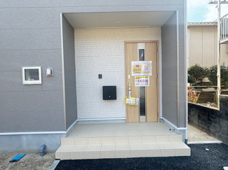 【玄関】 | 東広島市黒瀬切田が丘3丁目　1棟 | 木目調の玄関ドアがアクセントのスタイリッシュなポーチ。軒が深く、雨の日の出入りもスムーズです。モニター付きインターホンを完備し、防犯面にも配慮された清潔感のある玄関口となっています。