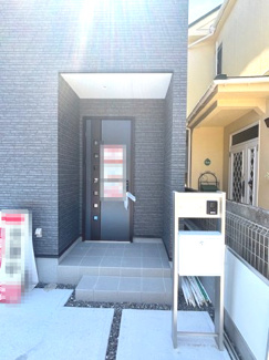 【玄関】 | 佐伯区美の里1丁目（楽々園電停）1号棟 | すっきりとしたスクエア型の門柱を設置した玄関アプローチ。ポーチ灯や軒が雨の日の出入りをサポートします。外壁に合わせた黒を基調とした、落ち着きのあるスタイリッシュなデザインです。