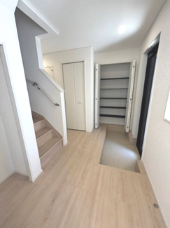 【玄関】 | 安芸郡熊野町城之堀1丁目　全10区画　NO10 | 可動棚付きの大型シューズボックスを備えた玄関。ホールには階段下のスペースを有効活用した収納もあり、ベビーカーやアウトドア用品の保管にも適しています。明るい木目調のフローリングが、清潔感を演出します。