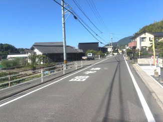 【前面道路含む現地写真】 | 廿日市市大野下更地（全3区画）No３ | 前面道路は「通学路」の標示があり、見通しの良い直線道路です。周辺は緑豊かな山々に囲まれた落ち着きのある住環境で、小さなお子様がいるご家庭も安心して暮らせる開放的な雰囲気が魅力です。