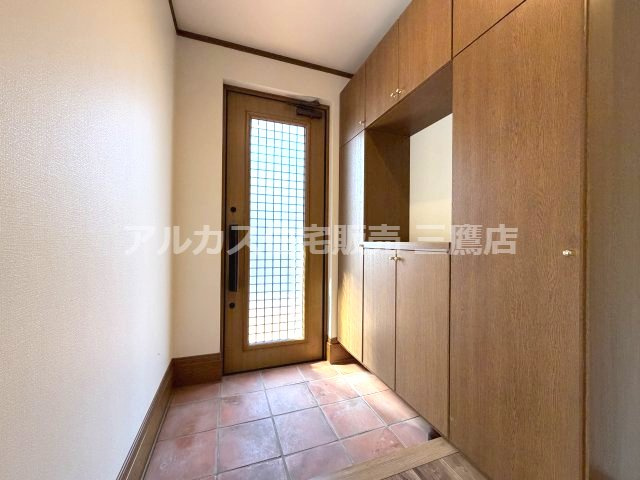 府中市紅葉丘1丁目 西武多摩川線 白糸台駅 中古戸建の玄関|テラコッタ調のタイルフロアと落ち着いた木目調の収納が迎える、上品な玄関アプローチ。