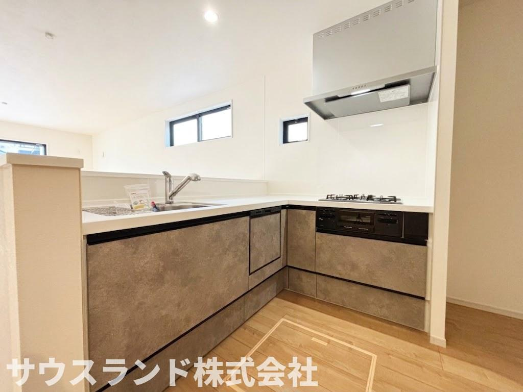 八王子市東浅川町6期１号棟のキッチン|落ち着いた色合いで統一されたお洒落なシステムキッチンです。背面には冷蔵庫やカップボードを置く十分なスペースが確保されています。ご家族でお料理を楽しむ際も、すれ違いやすいゆとりのある広さです。