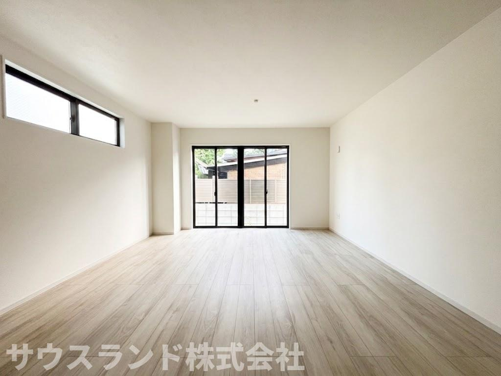 八王子市東浅川町6期2号棟の居間・リビング|床のフローリングは明るい色合いで、お部屋全体をより広く見せてくれます。大きな窓からお庭の緑が見え、室内にいながら自然の温もりを感じられます。毎日をリラックスして過ごせる、心地よいリビング空間です。