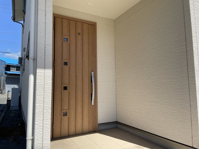 加古川市加古川町稲屋の玄関|【玄関】
温かみのある木目調の玄関ドアが採用されています。玄関ドアの横には傘立てなどを設置できるゆとりがあります。軒があり雨も当たりにくそうです。
