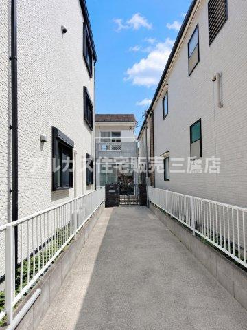 京王線 布田駅 17分 中古戸建 調布市染地2丁目の駐車場|アプローチ部分。白を基調とした壁面に囲まれたフラットな通路で、プライバシーに配慮された奥行きのある空間です。
