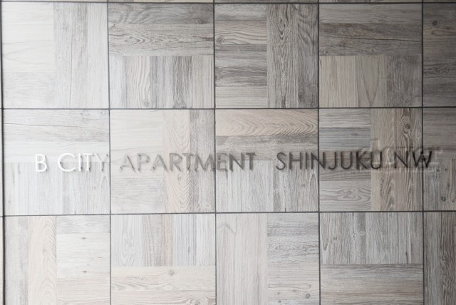 【現況写真】 | B CITY APARTMENT SHINJUKU NW | マンションの入り口に掲げられた、建物名称の表示部分。不動産業界ではこれを「館銘板」と呼びます。～即日のご見学可能～　お問合せはお気軽にどうぞ。
