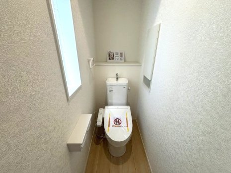 向洋新町2丁目のトイレ|温水洗浄機能付きトイレに窓と壁面収納を備えています。トイレットペーパーや清掃用品を手の届く場所へ整理しやすく、床まわりをすっきり保てます。窓は日中の換気にも利用できます。
