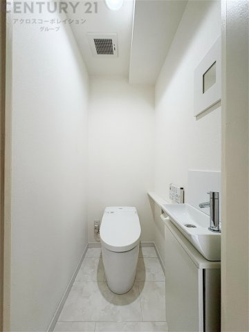清潔感あふれるホワイト基調のトイレ空間。便利な手洗いカウンターを備え、温水洗浄便座も完備。すっきりとしたデザインで、毎日気持ちよくお使いいただけます。