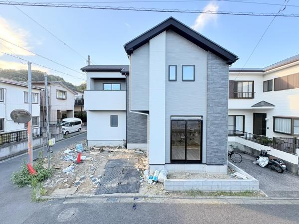 横浜市金沢区釜利谷南２丁目の新築一戸建の前面道路含む現地写真|シンプルな外観デザインが際立つ新築物件です。周囲に同系統の住宅が並び落ち着いたエリアに所在しています。前面道路は幅があり出入りがしやすい点も特長です。