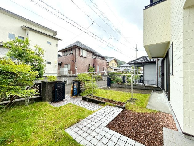「陽当り・通風良好な高台の住まい」吾川郡いの町天王南5丁目　中古一戸建ての庭|緑を感じる爽やかな玄関アプローチ。敷地内には心地よい緑が広がり、住まい全体に彩りを添えています。開放感あふれるアプローチが、住まう人や訪れる人を温かく迎え入れます。