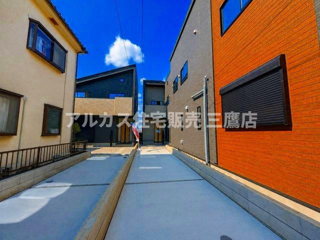 西武新宿線 新所沢駅 17分 新築戸建 所沢市向陽町の駐車場|敷地内の通路・駐車スペースと、隣接する住戸の外観アプローチ。
