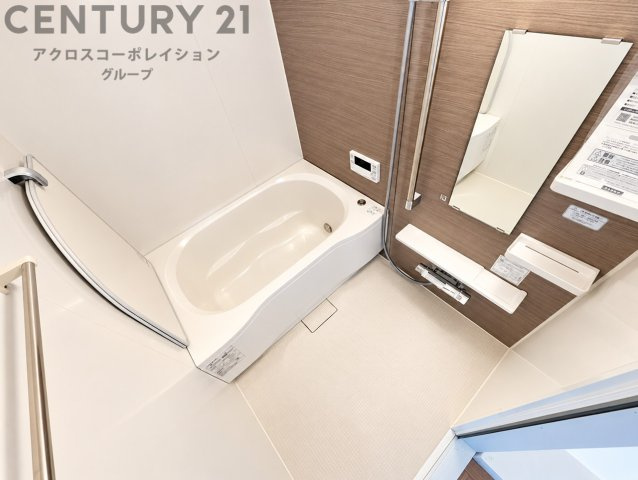 明るく清潔感あふれるバスルーム。木目調のアクセントパネルが温かみを演出します。大きな鏡や収納棚も備え、毎日のバスタイムを快適に過ごせる空間です。