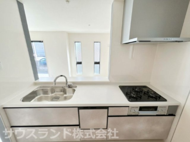 八王子市元横山町第1期 新築戸建てのキッチン|3口コンロを備えた使い勝手の良いシステムキッチンです！調理スペースが確保されており、一度に複数の料理を効率よく作ることができます。下部にはスライド式の引き出し収納があり大容量の器具もすっきり収まります