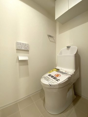 ライオンズマンション王子第６のトイレ|新規交換された清潔感のある温水洗浄便座付きトイレです。衛生的に保ちやすいデザインとなっており、快適にご使用いただけます。上部にはトイレットペーパー等を保管できる便利な収納棚を完備しています。