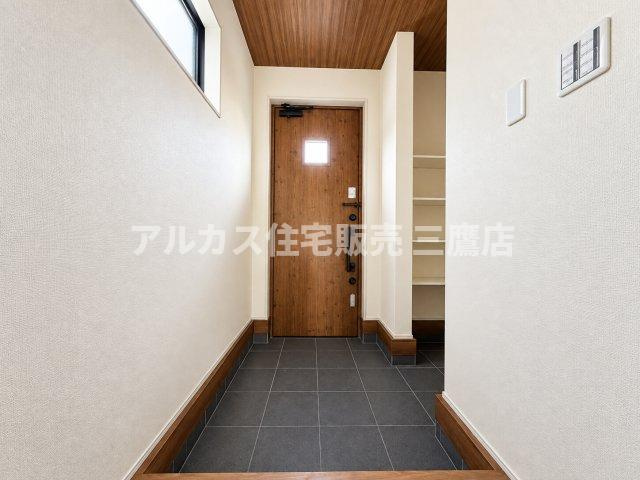 小平市上水本町2丁目　西武国分寺線　鷹の台駅　新築戸建の玄関|木目調のドアと落ち着いたトーンのタイルが温かみを感じさせる玄関ホール。土間続きの可動棚収納を備えており、靴や外出用品をすっきりと整理できます。