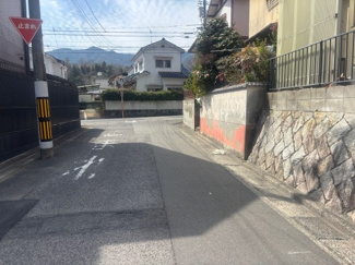 【前面道路含む現地写真】 | リナージュ八幡が丘2丁目（全1棟） | 物件前面は落ち着いた住宅街が広がる平坦な道路です。見通しが良く、車の出し入れもスムーズに行える幅員を確保。周辺は高い建物が少なく、空を広く感じられる開放的な住環境が魅力です。