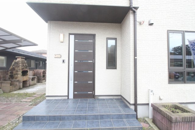 小山市出井の玄関|すっきりとしたデザインの玄関まわり。落ち着いた色合いの玄関ドアが、白を基調とした外観のアクセントになっています。