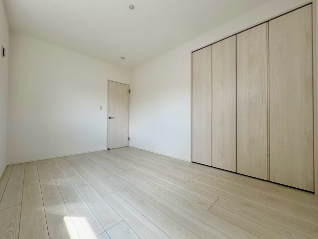 「スキップフロアと吹き抜けがある4LDK」高知市介良乙1号地　新築一戸建ての洋室|壁一面の大型クローゼットで室内スッキリ！ベッドや家具の配置がしやすいシンプルで明るい洋室。