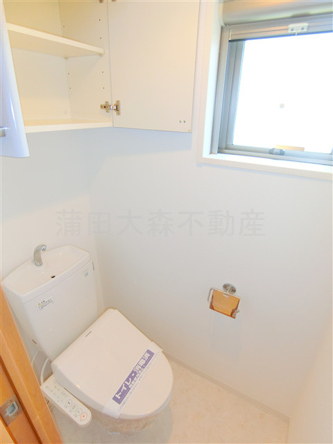 プロスペクト大森海岸のトイレ|窓と吊戸棚、温水洗浄便座付きのトイレ　