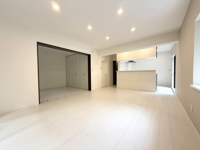 【居間・リビング】 | 光が丘パークタウン春の風公園街（成増店） | 広々17.4帖の大空間LDK。白を基調としたスタイリッシュな内装とダウンライトが、明るく開放的な雰囲気を演出します。ご家族が集い、ゆったりと寛げる心地よいリビングです。