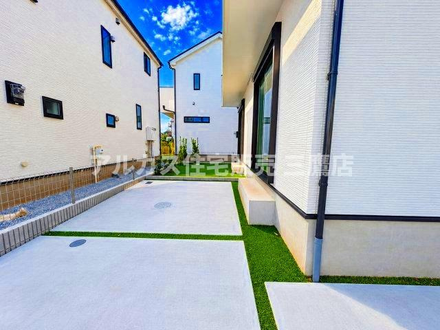 国分寺市北町3丁目　西武国分寺線　鷹の台駅　新築戸建の駐車場|コンクリート敷きで整えられた駐車スペース。奥には人工芝が広がり、整然とした印象を与えます。