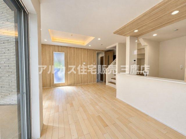 三鷹市井口4丁目 西武多摩川線 新小金井駅 新築戸建の居間・リビング|空間に奥行きを感じさせるスタイリッシュなLDK。木目調アクセントウォールがお部屋全体を温かい印象に引き立てます。