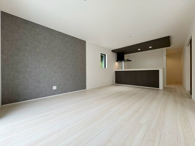 「南西角地の平屋」高知市瀬戸西町2期1棟　新築一戸建ての居間・リビング|モダンなアクセントクロスが映えるリビング。ダウンライトの優しい灯りが心地よい空間を演出します。