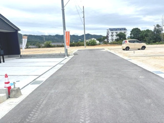 【前面道路含む現地写真】 | 東広島市高屋町高屋東（全2区画）2号棟 | 前面道路はアスファルト舗装が施され、すっきりとした印象です。お車の出し入れもスムーズに行えそうな、ゆとりある幅員が確保されています。